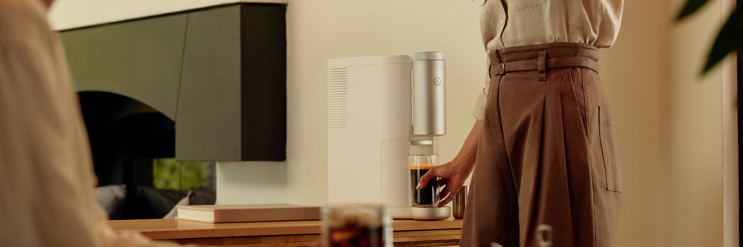 A woman grabbing a glass of Cumulus Coffee out of a Cumulus Machine on a countertop