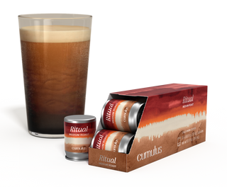 An opened pack of Ritual medium roast coffee capsule next to a cup of coffee