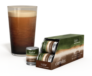 An opened pack of Valor medium-dark roast coffee capsule next to a cup of coffee