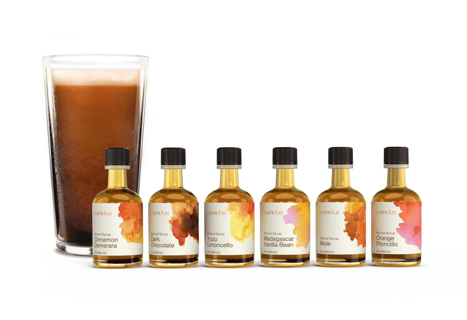 A set of six cumulus flavor syrup bottles sitting in front of a cup of cold brew coffee. The labels say "Cinnamon Demerera", "Dark Chocolate", "Yuzu Limoncello", "Madagascar Vanilla Bean", "Mole" and "Orange Piloncillo"