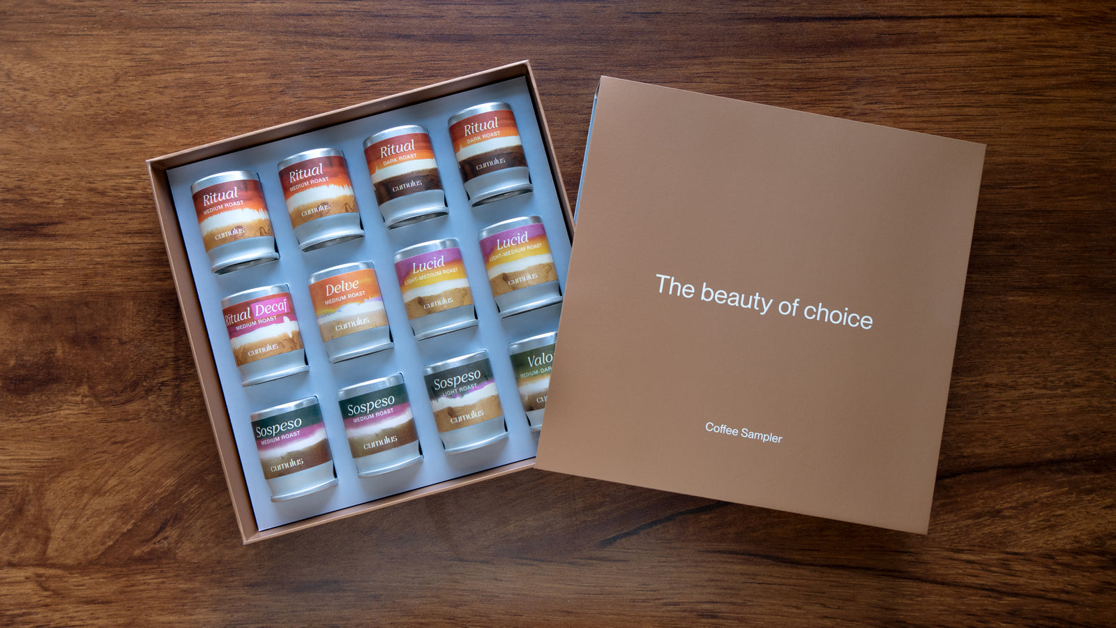 An open box containing 12 flavor capsules with various flavors. The label on the box says "The beauty of choice" and "coffee sampler"