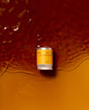 A flavor capsule laying partially submerged in coffee as if on a beach. The flavor is "Wush Wush - light medium roast"