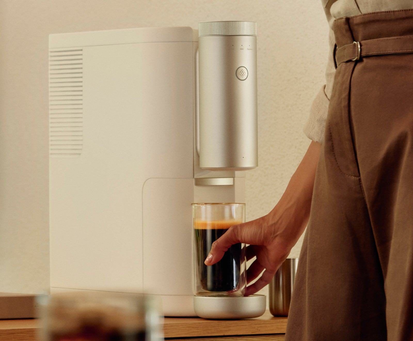 A person retrieving a completed cup of coffee from a Cumulus machine