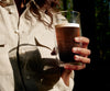 A zoomed shot of a woman holding a cup of coffee