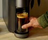 A hand retriving a cup of coffee from the Cumulus machine