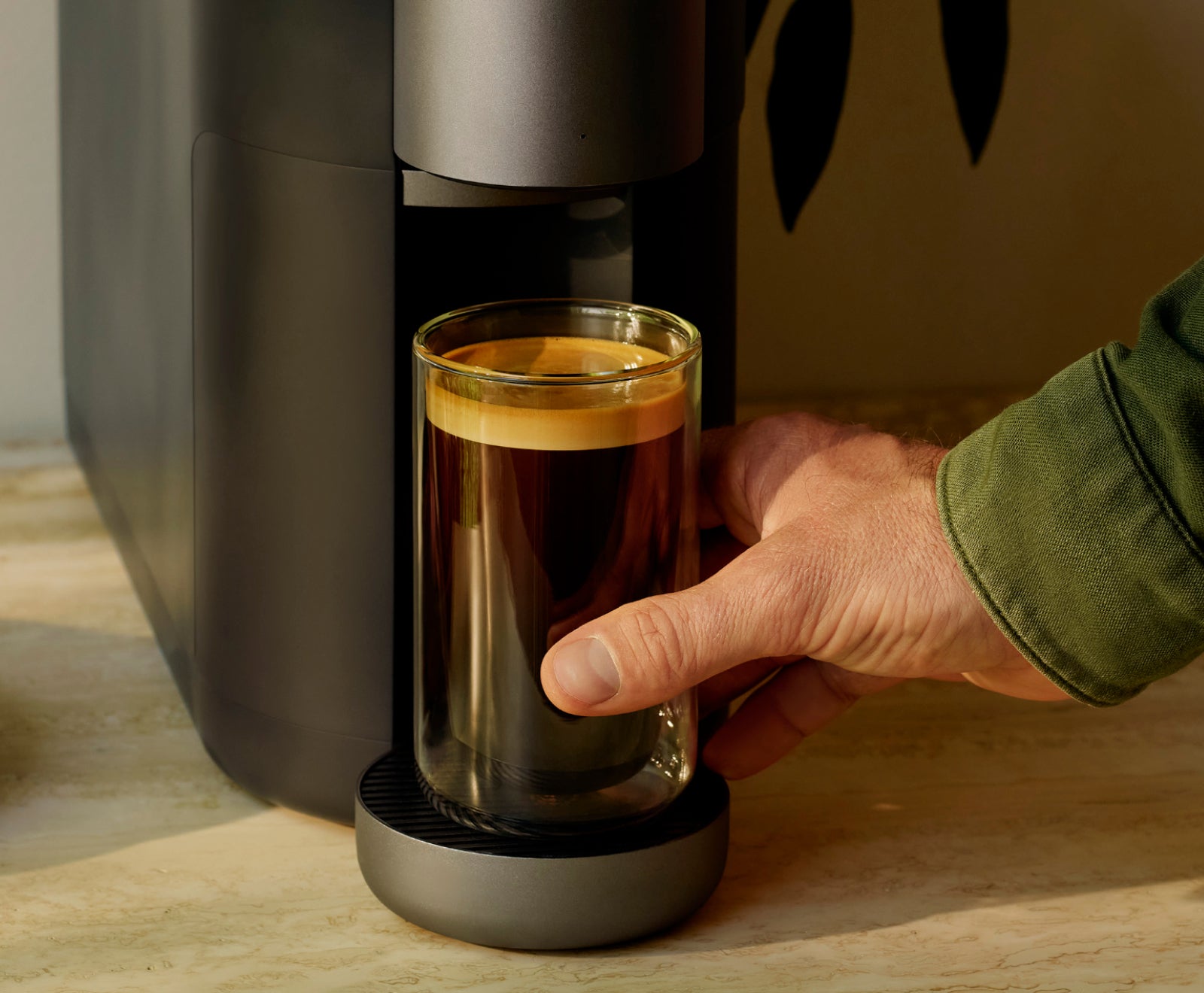 A hand retriving a cup of coffee from the Cumulus machine